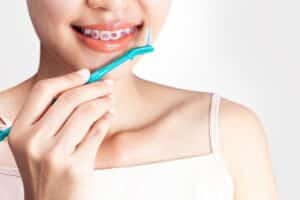 person cleaning her braces with dental brush