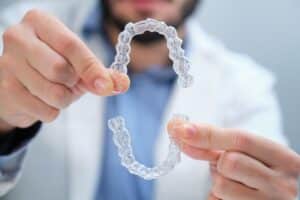 person with aligner trays in hand
